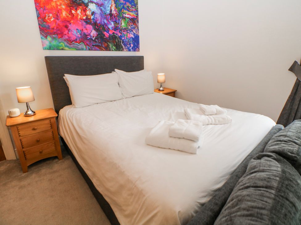 A bedroom featuring a bed with pillows, bedside tables and wall art at Arkwright Matlock