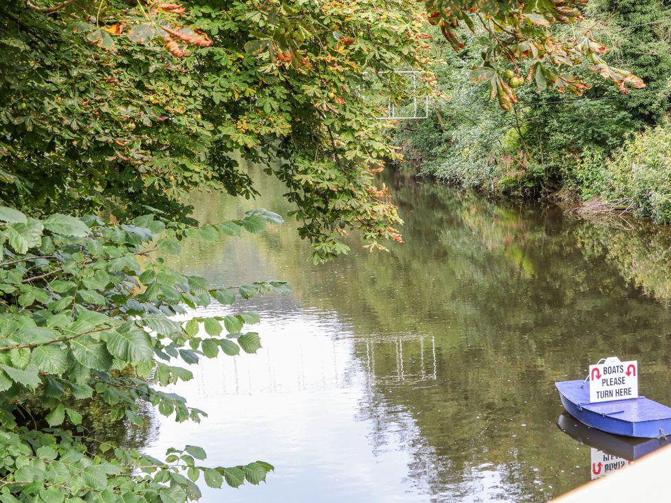 A river with a boat and a sign at Lumsdale in Matlock Bath