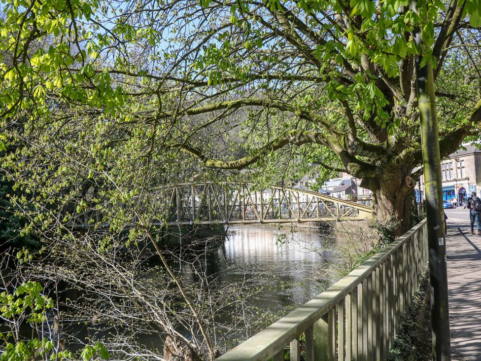 A bridge over a river with trees and buildings in the background at Lumsdale Matlock Bath