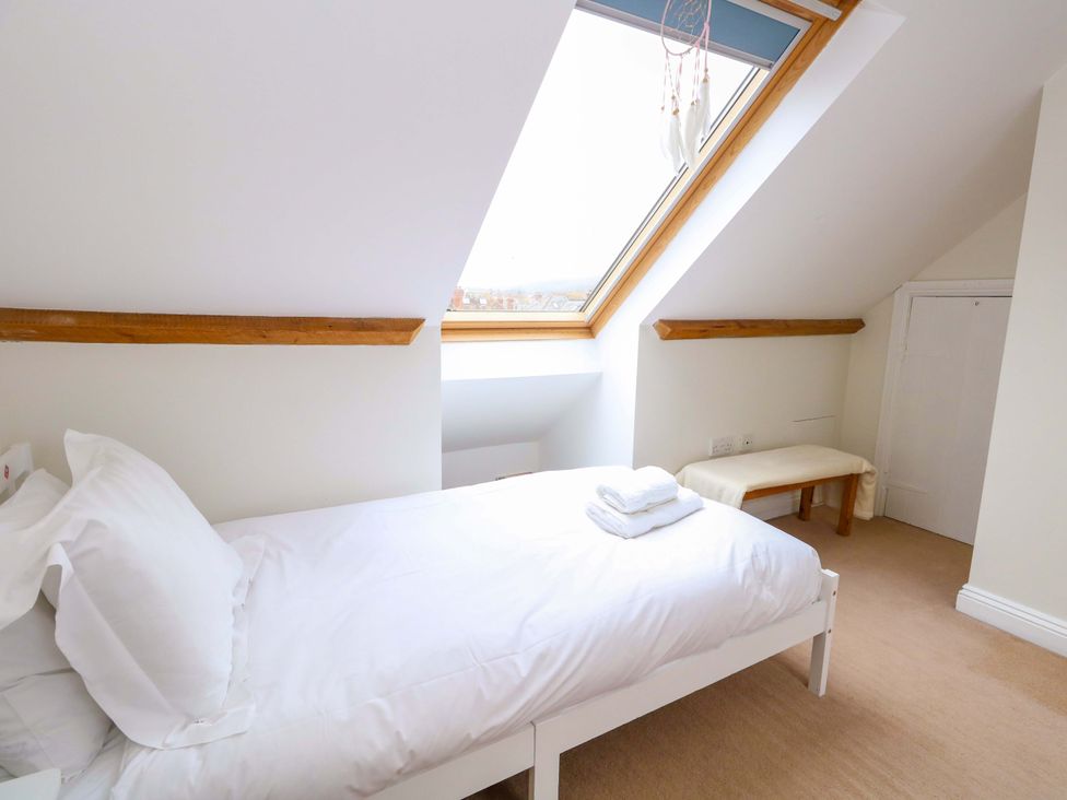 A bedroom with a bed, window, and bench at Garden Retreat in Swanage