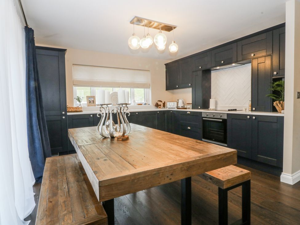 A kitchen with a wooden table and dark cabinets at Tyn Y Coed