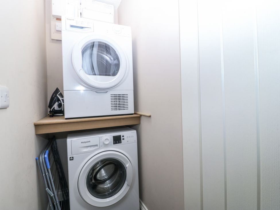 A washing machine and dryer stacked in a laundry room at Tyn Y Coed