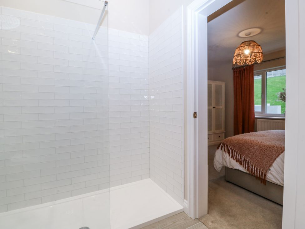 A bathroom with a shower and a view into a bedroom at Tyn Y Coed