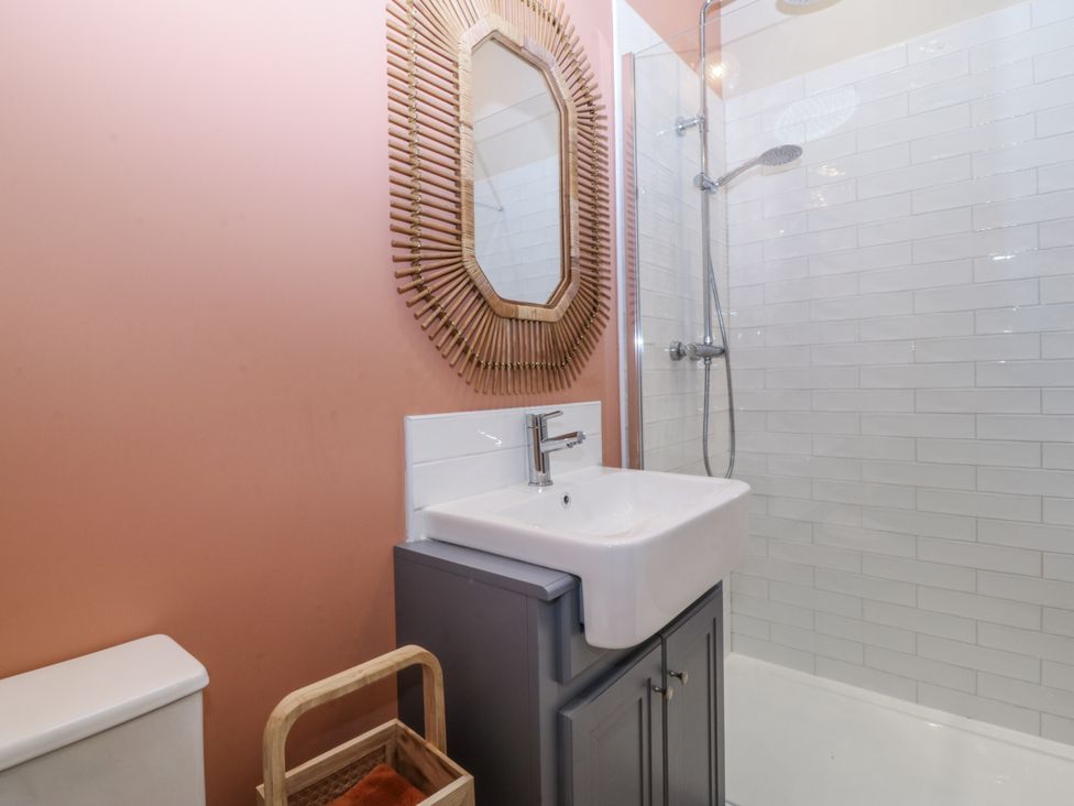 A bathroom with a sink, toilet, shower and mirror at Tyn Y Coed