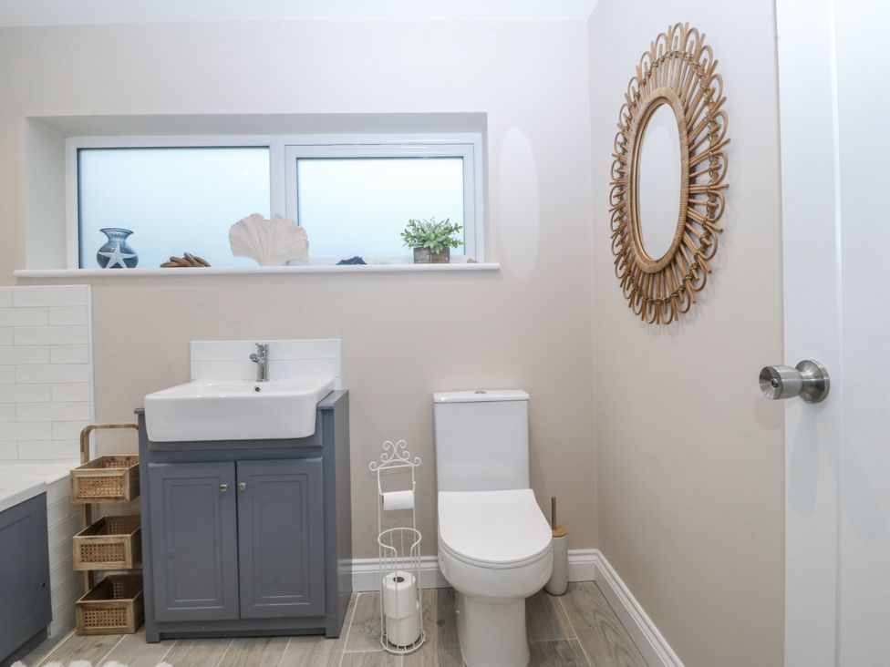 A bathroom with a sink, toilet, and window at Tyn Y Coed 