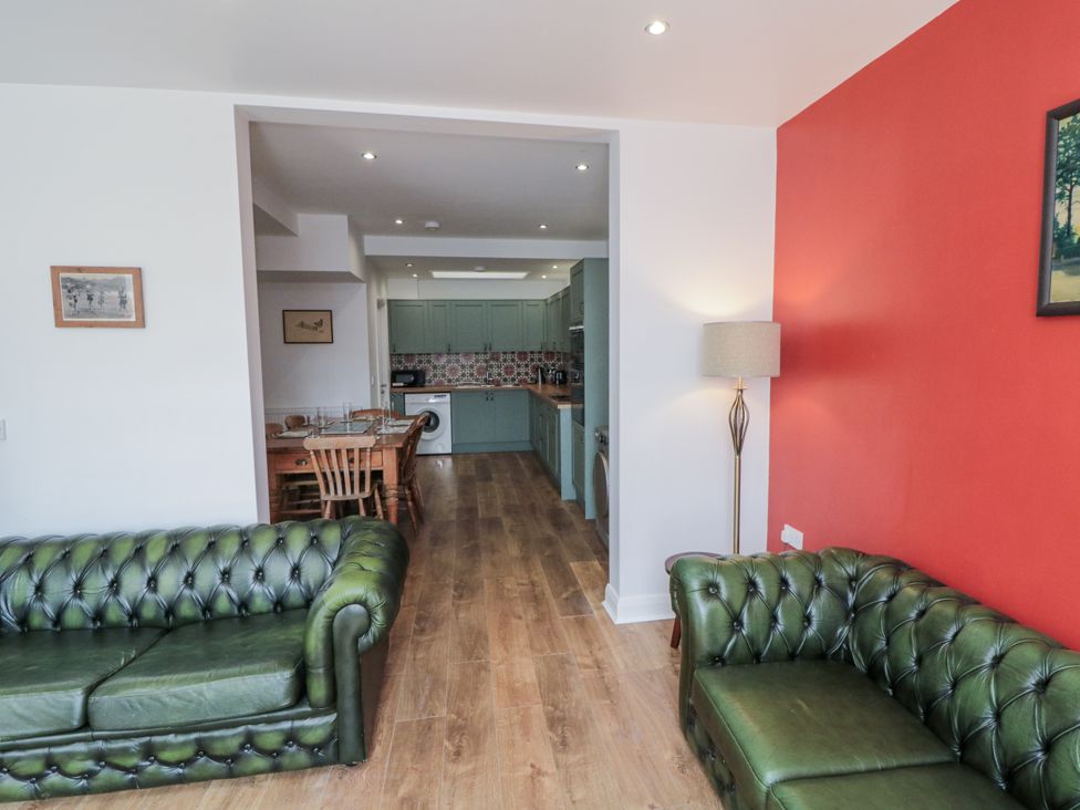 A living room with green sofas and a view of the kitchen at Number 33 in Scarborough