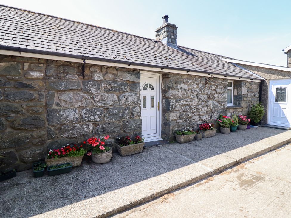 An exterior view of a stone cottage with potted plants at Ysgubor Newydd Parc Isaf Dyffryn Ardudwy