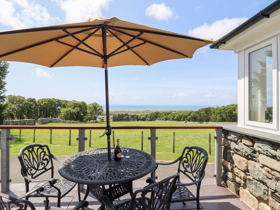 An outdoor space with a table and chairs under an umbrella at Ysgubor Newydd Parc Isaf Dyffryn Ardudwy
