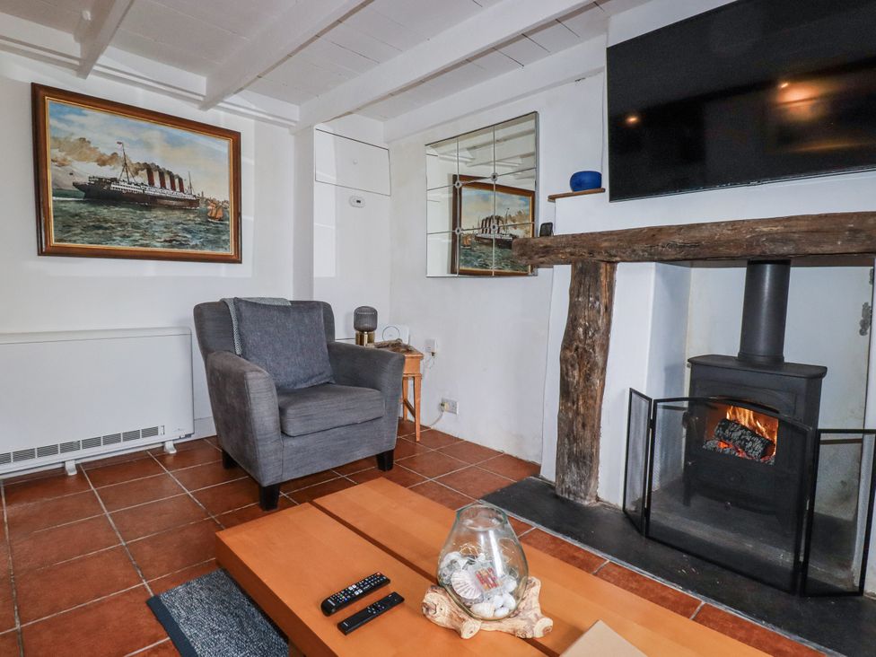 A living room with an armchair and fireplace at Rose Cottage in Falmouth