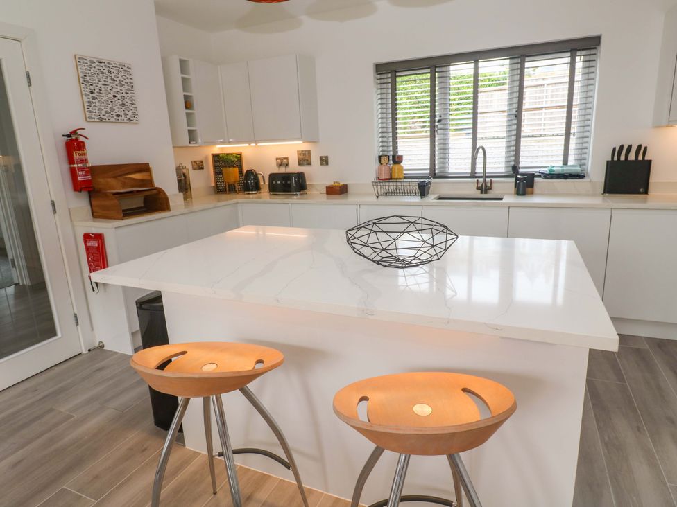 A kitchen with an island and bar stools at Miramar in St. Ives