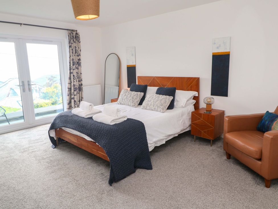 A bedroom with a bed and armchair at Miramar in St. Ives