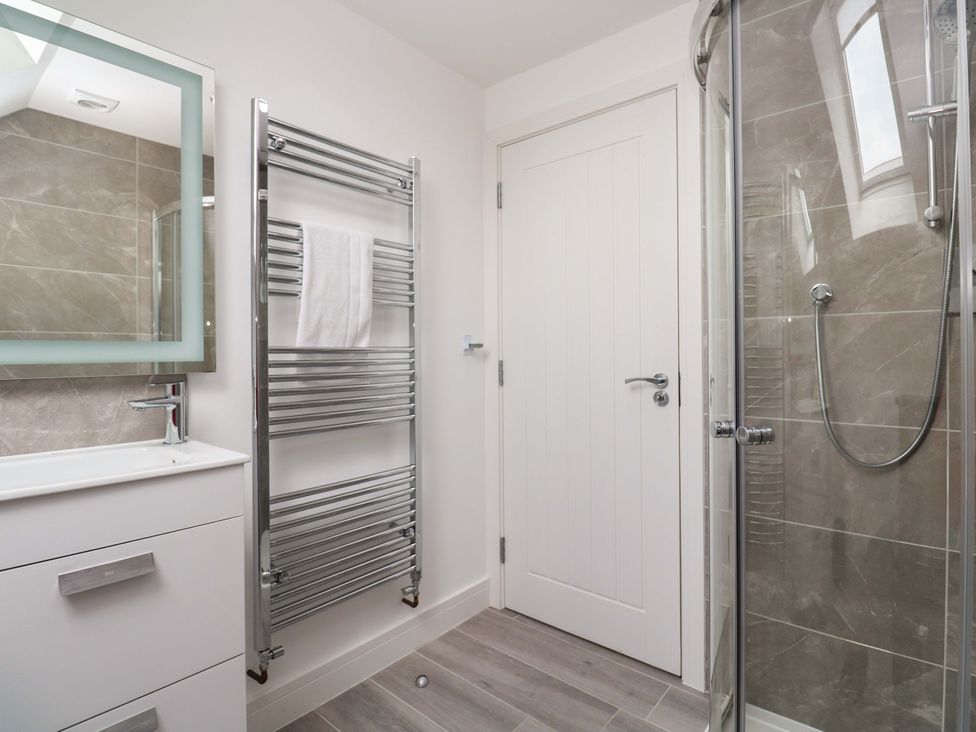 A bathroom with a sink, mirror, shower, and towel rail at Miramar in St. Ives