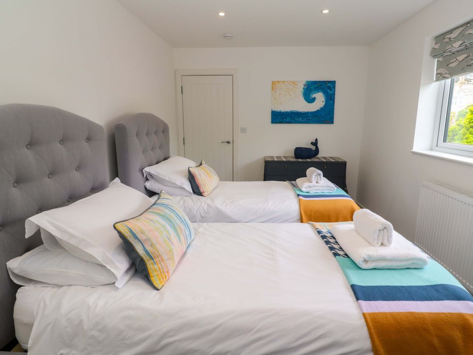 A bedroom with two beds and artwork at Miramar in St. Ives