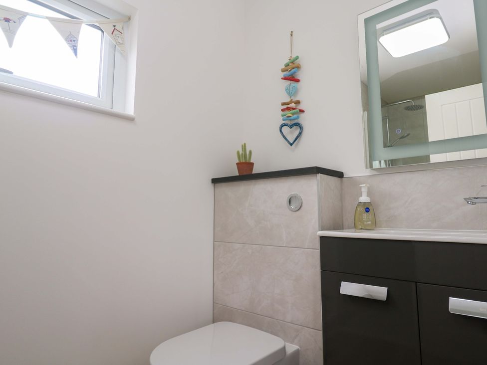 A bathroom with a toilet, sink, and mirror at Miramar in St. Ives