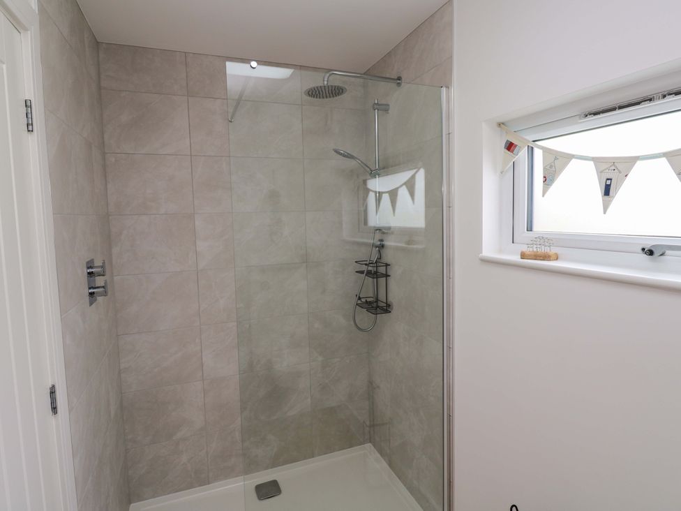 A shower with glass enclosure and tiled wall at Miramar in St. Ives