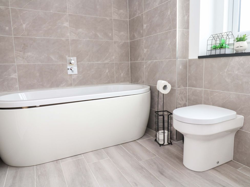 A bathroom with a bathtub and toilet at Miramar in St. Ives