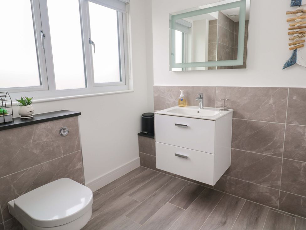 A bathroom with a sink, toilet, and mirror at Miramar in St. Ives