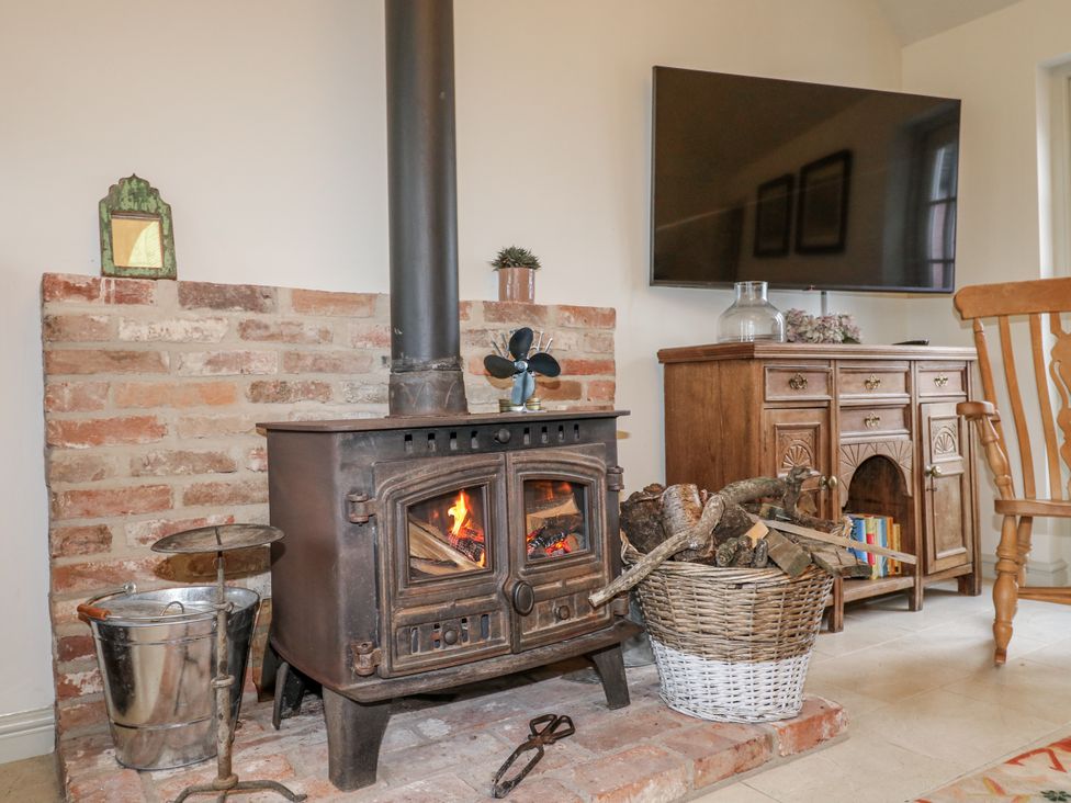 A living room with a wood stove and television at Gapstile in Abbots Bromley