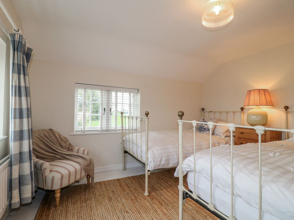 A bedroom with two beds and a chair at Gapstile in Abbots Bromley