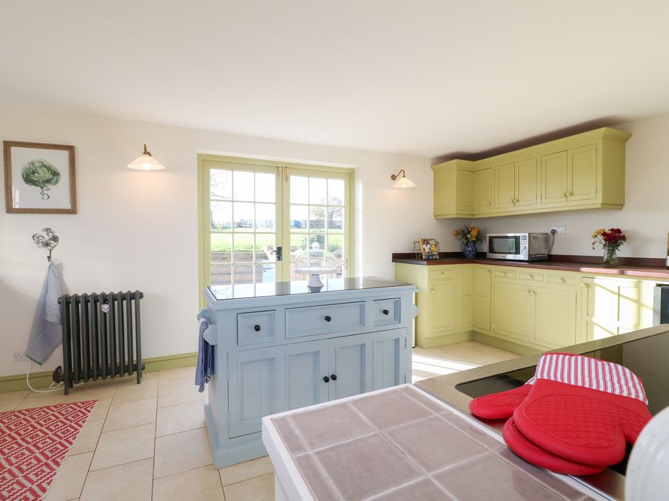 A kitchen with a blue island and green cabinets at Gapstile in Abbots Bromley