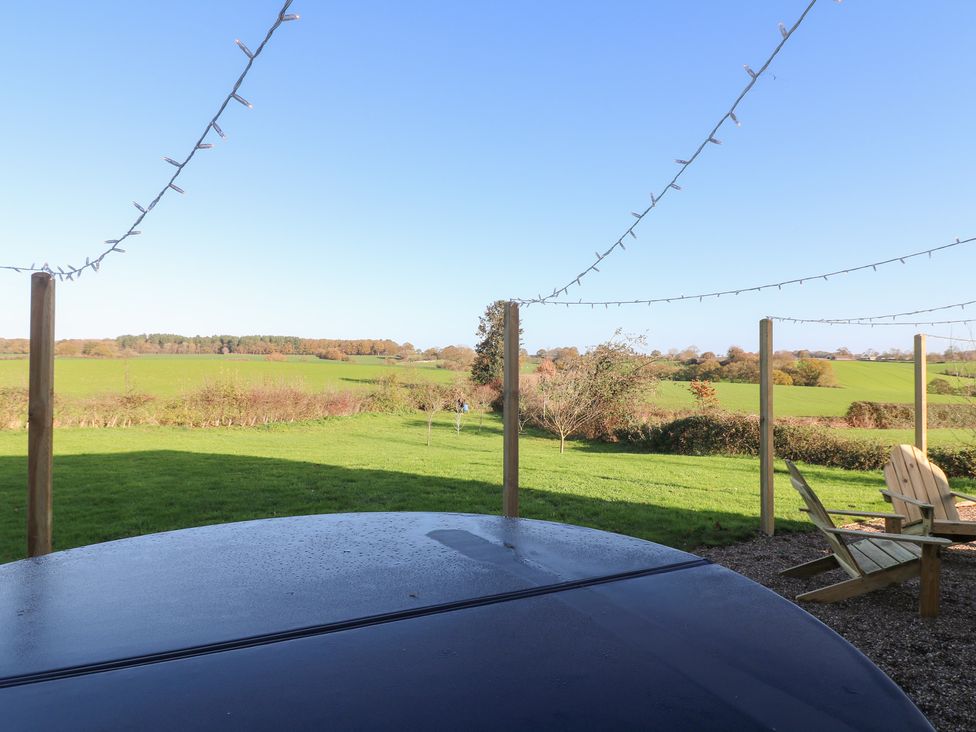 A garden view with a field and a wooden chair at Gapstile in Abbots Bromley
