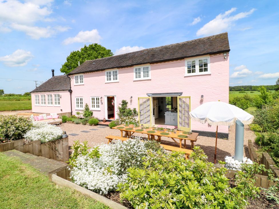 An outdoor space with a pink house and table at Gapstile in Abbots Bromley