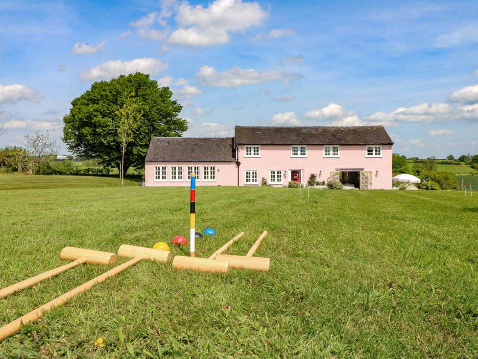 An outdoor area with a pink house and a croquet set at Gapstile in Abbots Bromley