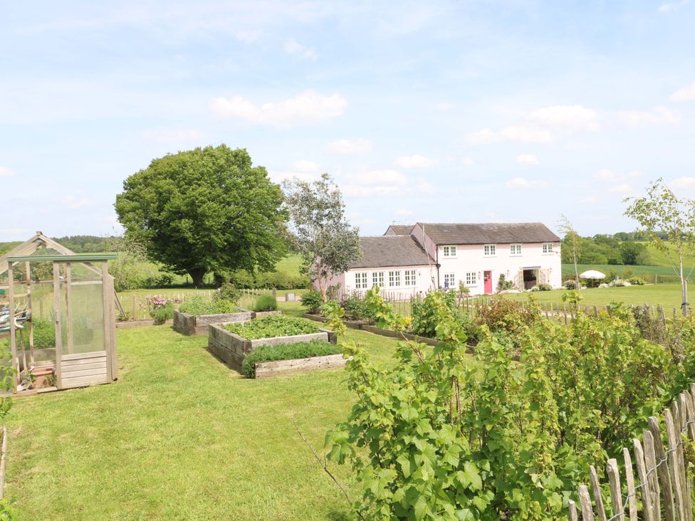 A garden with a greenhouse and vegetable beds at Gapstile in Abbots Bromley