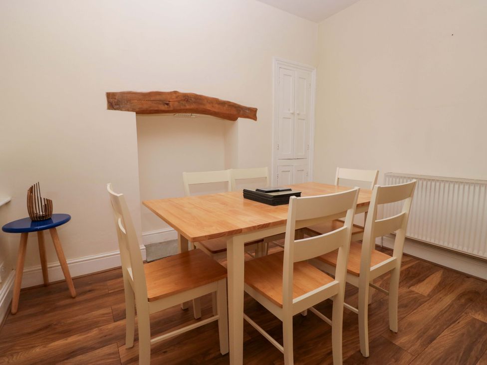 A dining room with a wooden table and six chairs at 28 Rock Villas in Carnforth