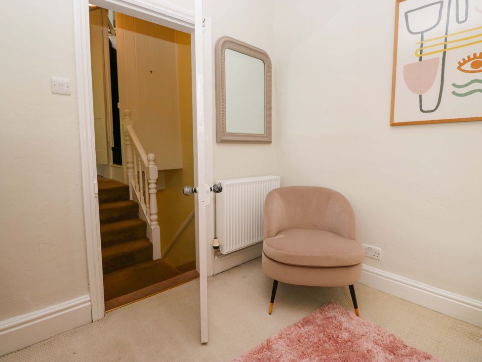 A hallway with a chair and stairs at 28 Rock Villas Carnforth