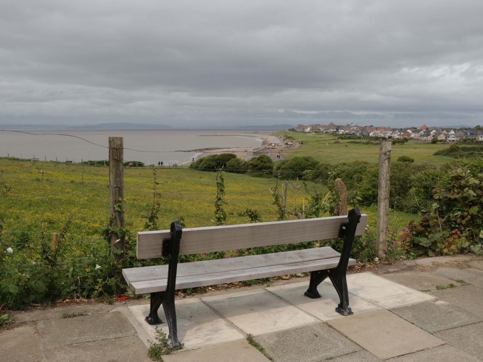 A bench overlooking a field and water at 28 Rock Villas in Carnforth
