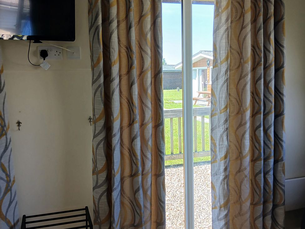 A living room with a television and curtains at Gwanda in Tregolds near St Merryn