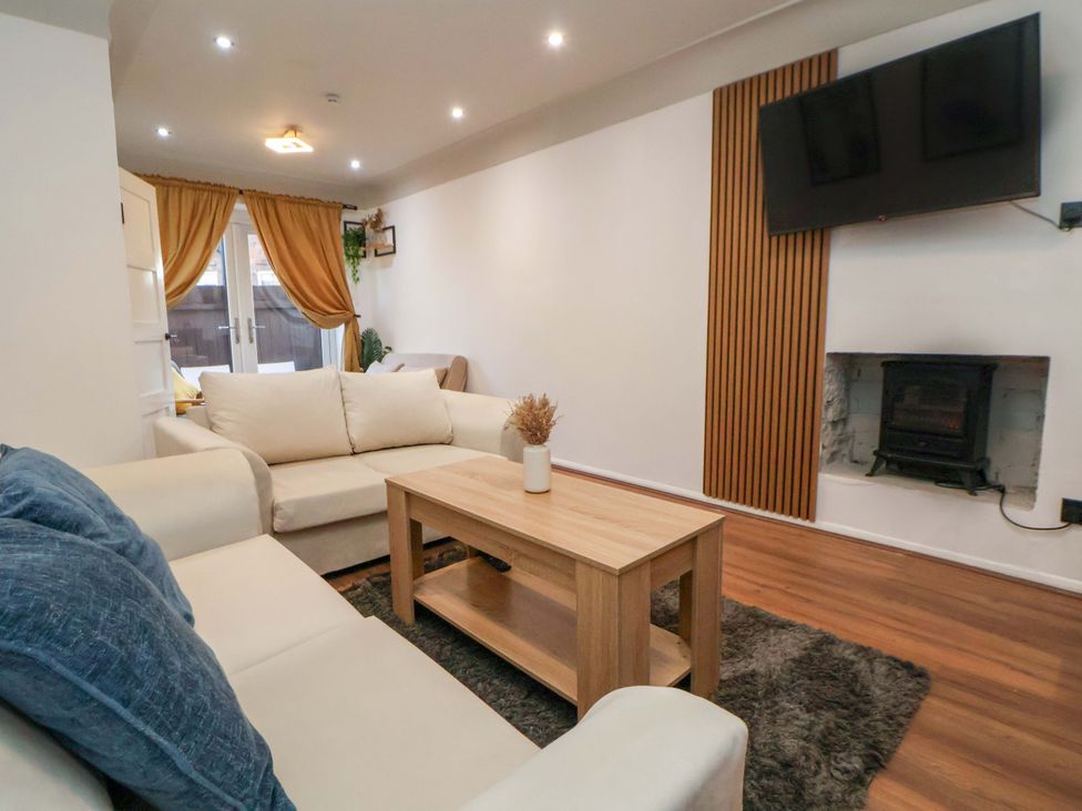 A living room with sofa, coffee table, television, and curtains at The Cloud House @ Hoole