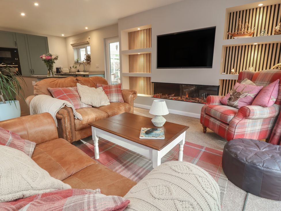 A living room with a sofa, armchair, coffee table, and television at Little Willesleigh in Goodleigh near Barnstaple