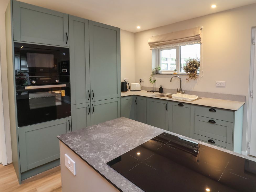 A kitchen with cabinets, appliances and a sink at Little Willesleigh in Goodleigh near Barnstaple