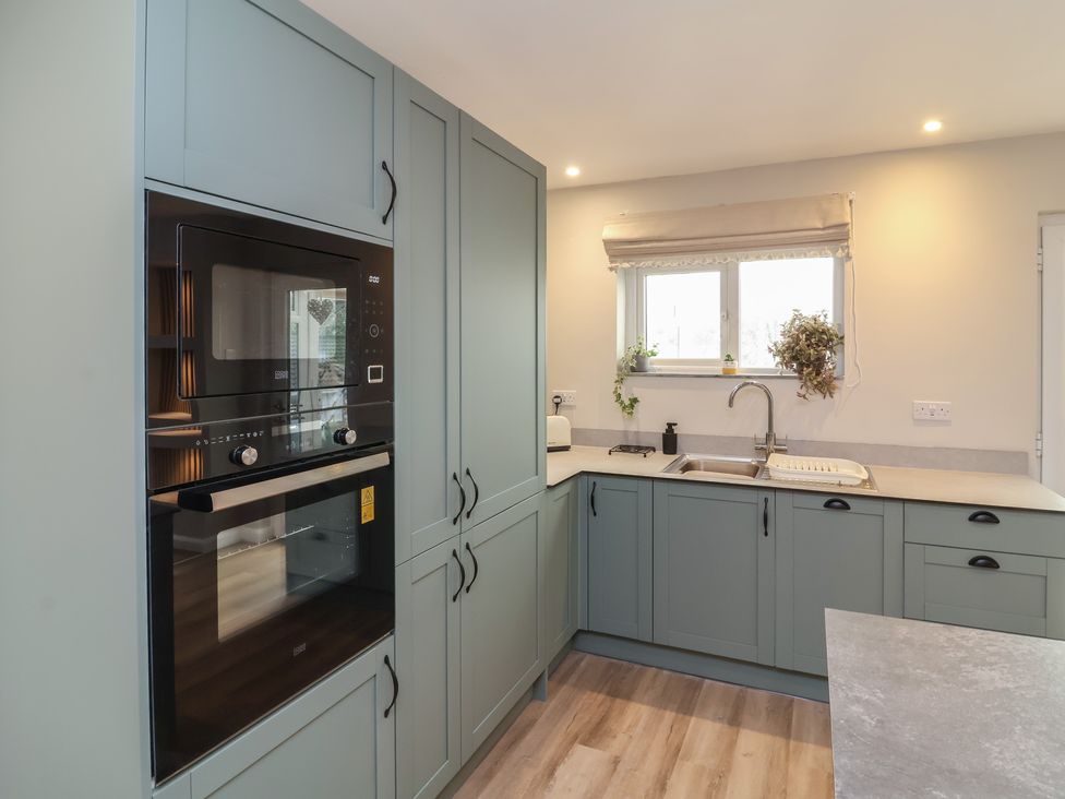 A kitchen with an oven, microwave, and sink at Little Willesleigh in Goodleigh near Barnstaple