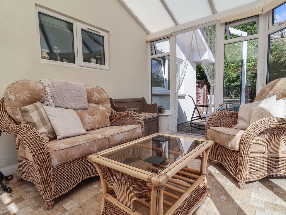 A conservatory with wicker furniture and a glass table at Little Willesleigh in Goodleigh near Barnstaple