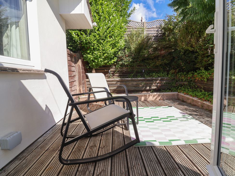 A patio with a rocking chair and rug at Little Willesleigh Goodleigh near Barnstaple