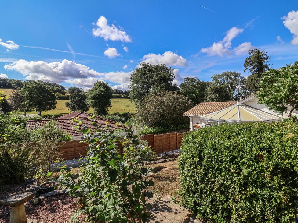 A garden with trees and a conservatory at Little Willesleigh in Goodleigh near Barnstaple