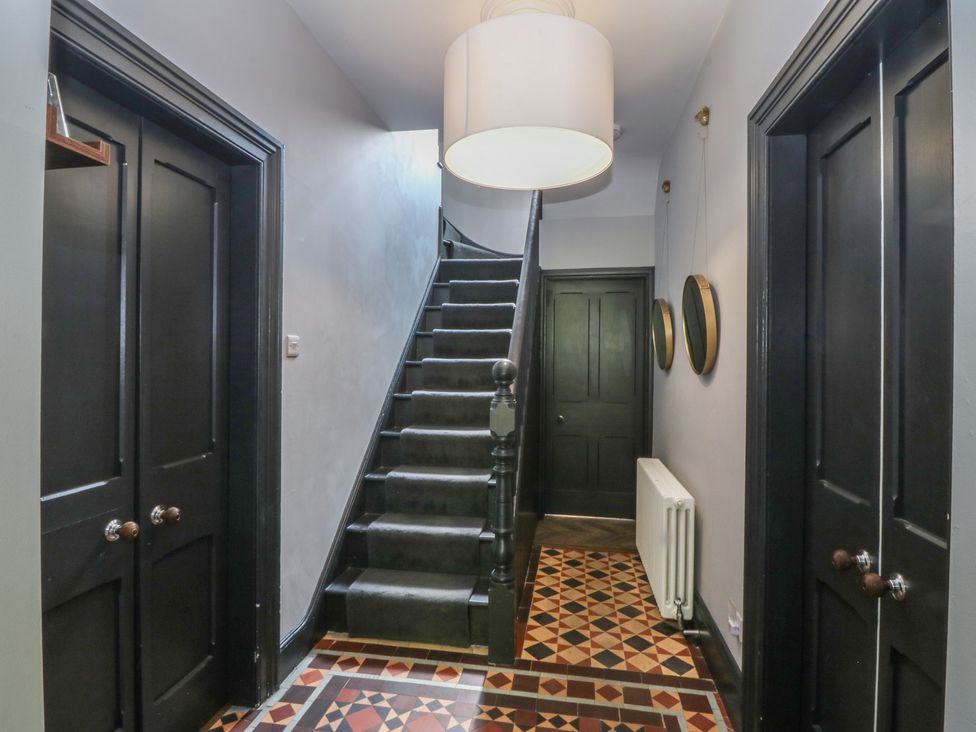 A hallway with a staircase and light fixture at Gweryl Lodge in Conwy