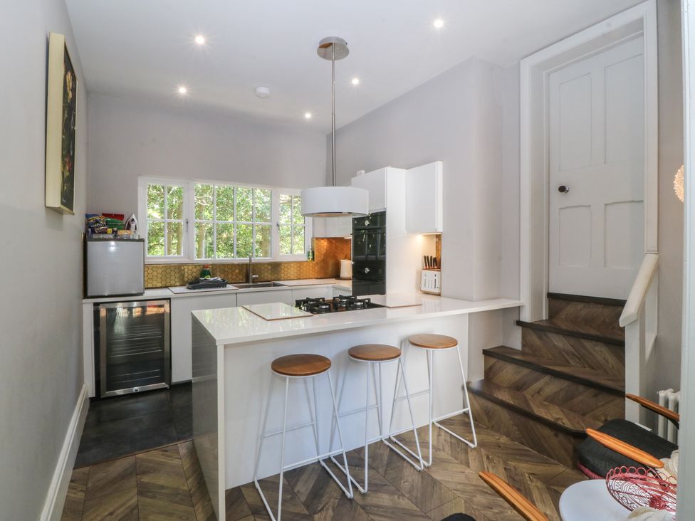 A kitchen with stove and bar stools at Gweryl Lodge in Conwy