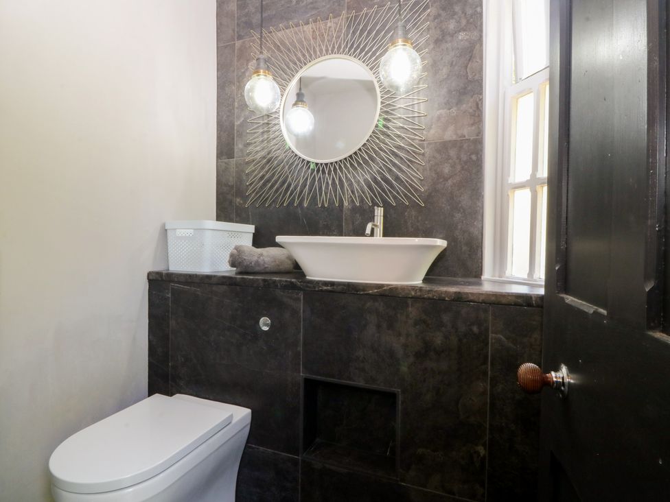 A bathroom featuring a sink, toilet, and mirror at Gweryl Lodge in Conwy