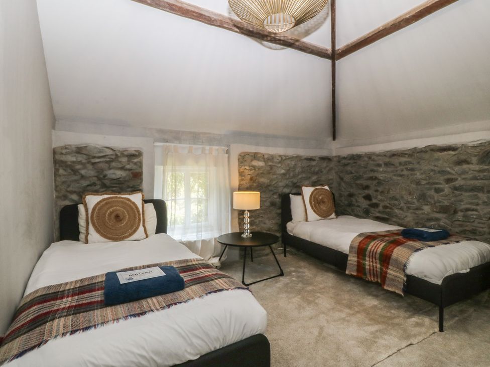 A bedroom with two beds and a lamp at Gweryl Lodge in Conwy