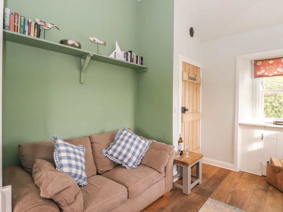 A living room with a sofa and books on a shelf at South Lodge in Ardpatrick near Tarbert