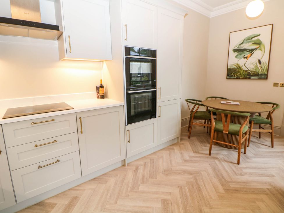 A kitchen with cabinets and a dining area at Pavilion Suite in Buxton
