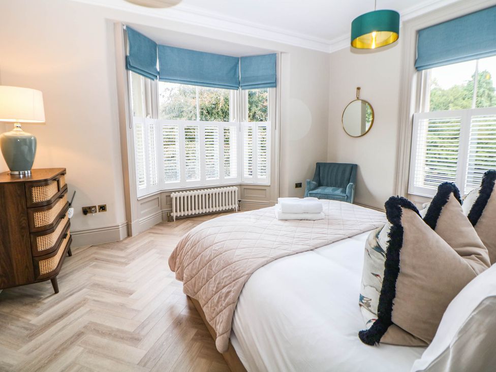A bedroom with a bed, chair, and lamp at Pavilion Suite, Buxton