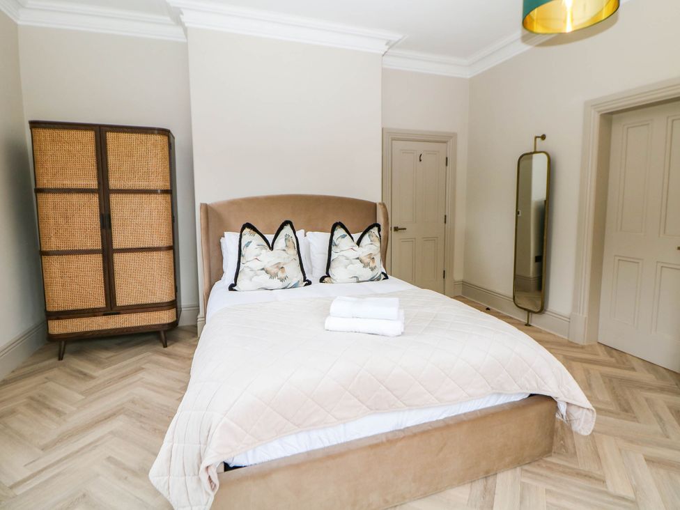 A bedroom with a bed, wardrobe, and mirror at Pavilion Suite in Buxton