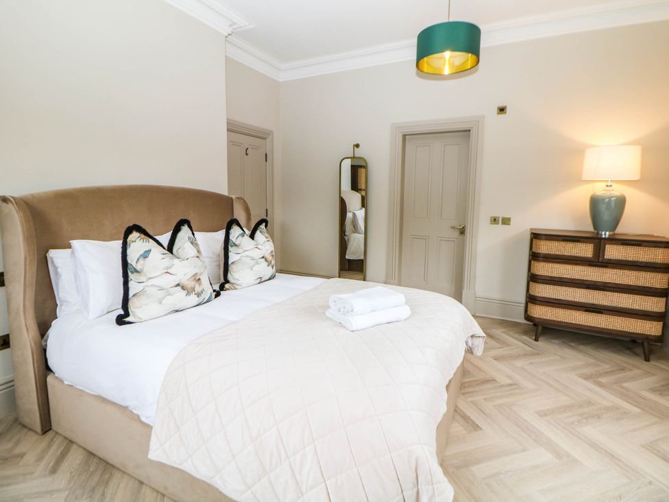 A bedroom with a bed, dresser, and lamp at Pavilion Suite Buxton