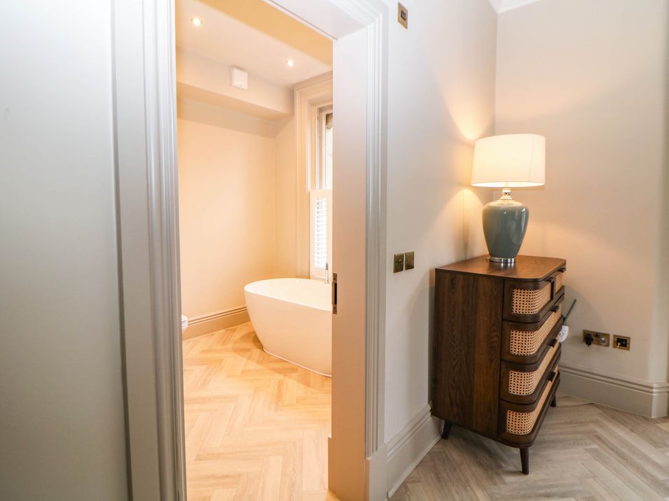 A bathroom with a bathtub visible from an adjoining room at Pavilion Suite in Buxton