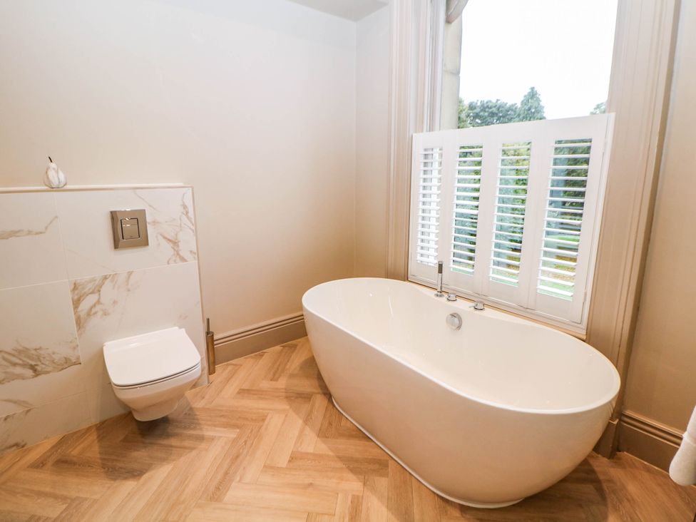 A bathroom with a bathtub and toilet at Pavilion Suite Buxton